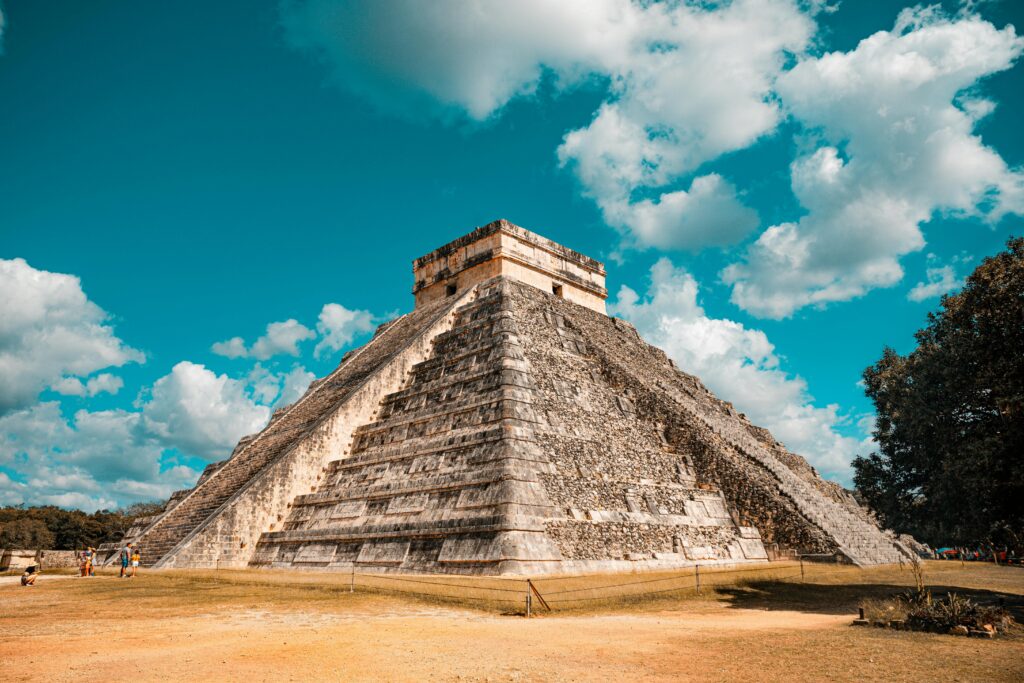 The iconic El Castillo pyramid at Chichen Itza, Mexico, captured on a sunny day with a vibrant blue sky.