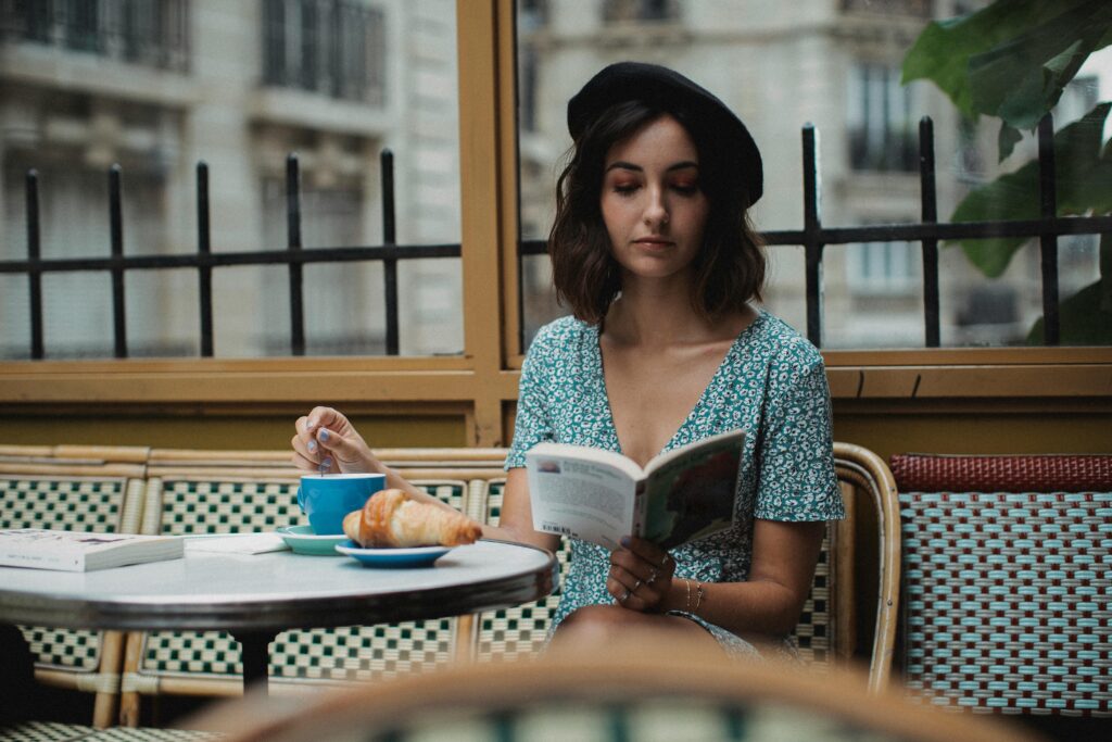 pexels photo 5177507 5177507 A woman enjoys a book with coffee at a Parisian cafe, exuding a calm and classic ambiance.